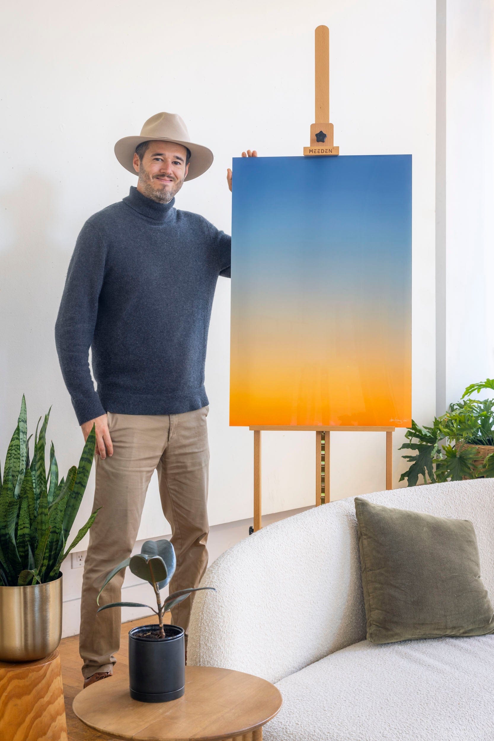 West Seattle artist Lars Gesing with a piece of his Big Sur Wall Art showing a sunset photo.