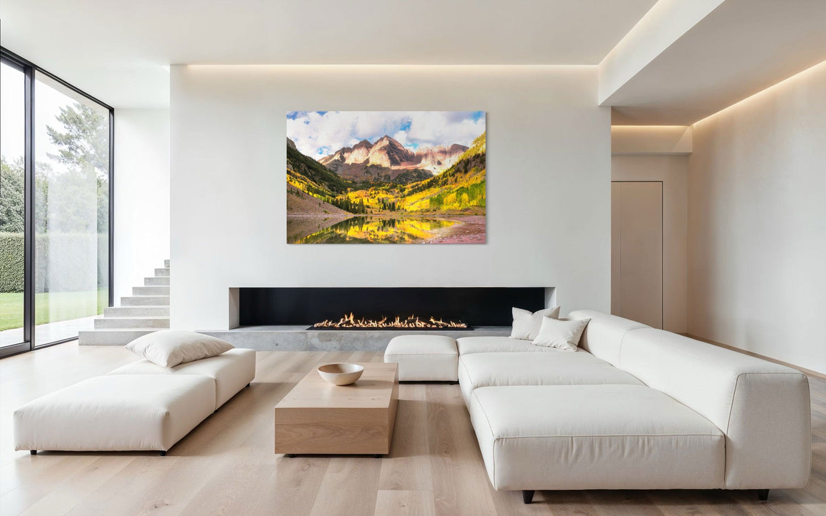 Stunning artwork of the Maroon Bells in Aspen during fall hangs above a fireplace in a modern home.