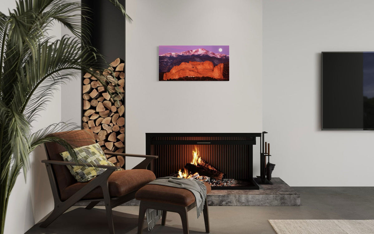 A piece of Colorado art showing a photo of Pike's Peak and the Garden of the Gods in Colorado Springs hangs above a modern firepalce.