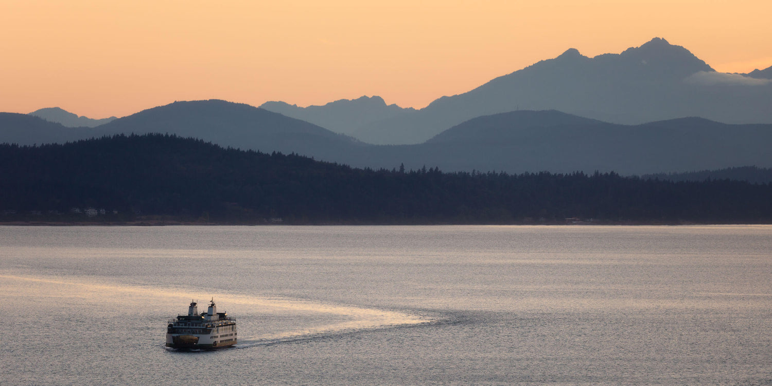 A Seattle sunset picture of a ferry coming from the Olympic Mountains.