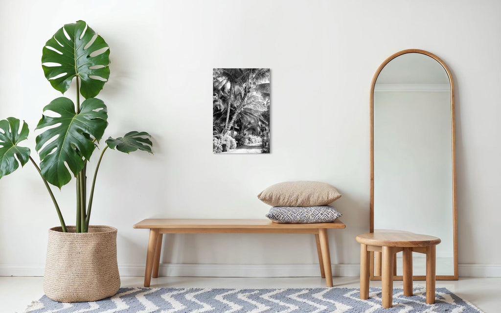 A piece of black and white Kauai art showing Anini Road hangs above a bench.