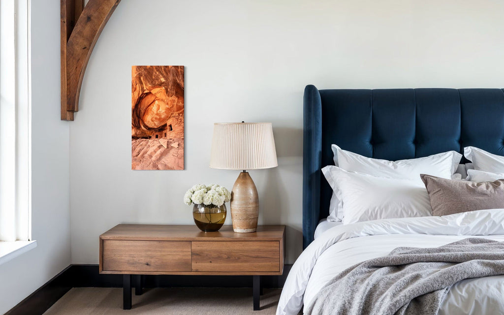 A piece of Southwest art showing a photo of an Anasazi dwelling in Bears Ears National Monument hangs above a bedside table.