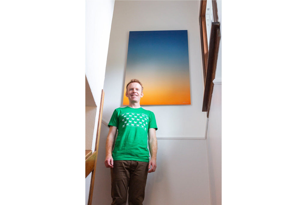 A piece of Lars Gesing's Big Sur Wall Art showing a sunset photo hangs in a collector's staircase.