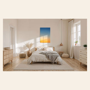A piece of Big Sur Wall Art showing a sunset photo hangs in a bedroom.