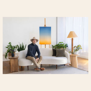 West Seattle artist Lars Gesing with piece of his Big Sur Wall Art showing a sunset photo.