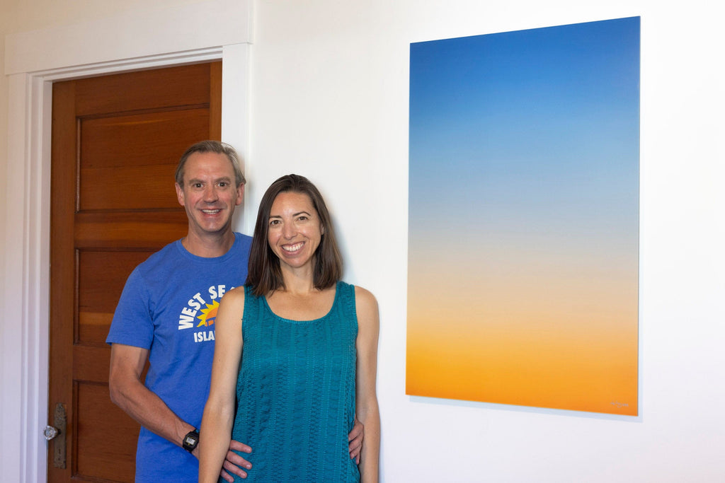 A piece of Lars Gesing's Big Sur Wall Art showing a sunset photo hangs in a collector couple's bedroom.