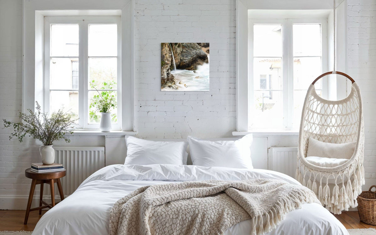 A piece of Big Sur art showing a waterfall photo hangs in a bedroom.