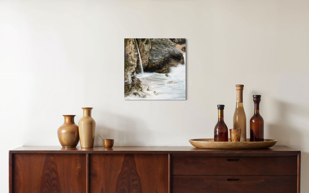 A piece of Big Sur art showing a waterfall photo hangs over a console.