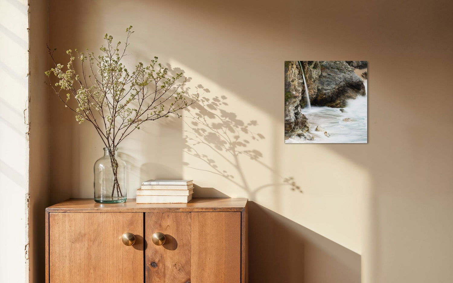 A piece of Big Sur art showing a waterfall photo hangs in a home.
