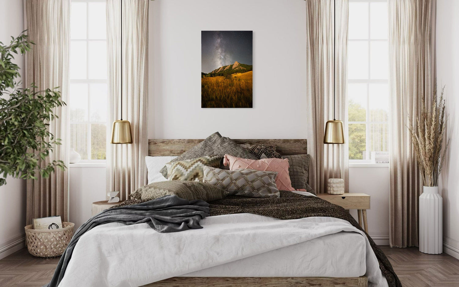 A piece of Boulder art showing the Flatirons with the Milky Way above hangs over a bed.