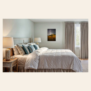 A piece of Boulder art showing the Flatirons with the Milky Way above hangs in a bedroom.