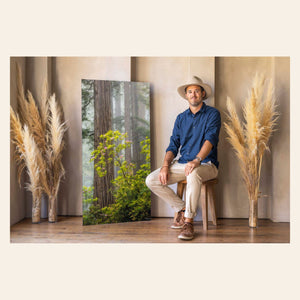 PNW artist Lars Gesing with a piece of large wall art showing a California redwoods photo.