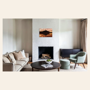 A piece of Crested Butte art showing a photo of the mountain at sunrise from Peanut Lake hangs above a fireplace.