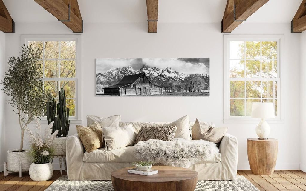 A piece of black and white wall art from Grand Teton National Park hangs in a living room with wood beams on the ceilings.