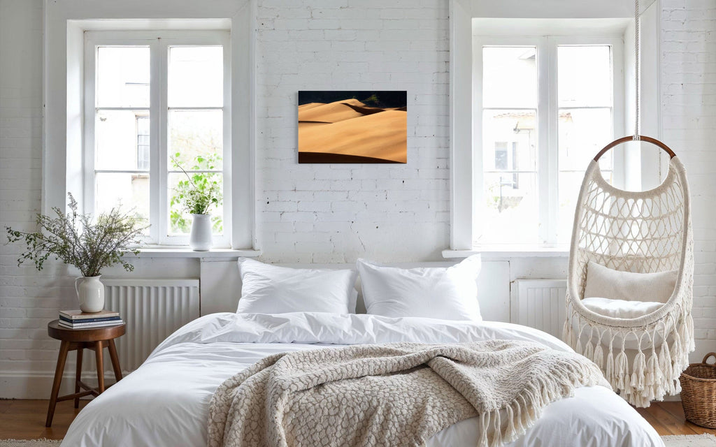 A piece of Colorado art showing a photo of Great Sand Dunes National Park hangs above a bed.
