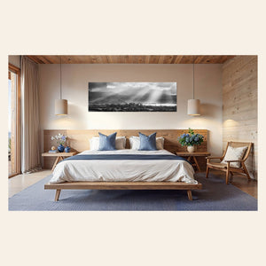A piece of Hanalei black and white Kauai art hangs above a bed.