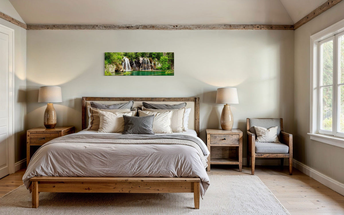 A piece of Colorado art showing a photo of the Hanging Lake waterfall hangs above a bed.