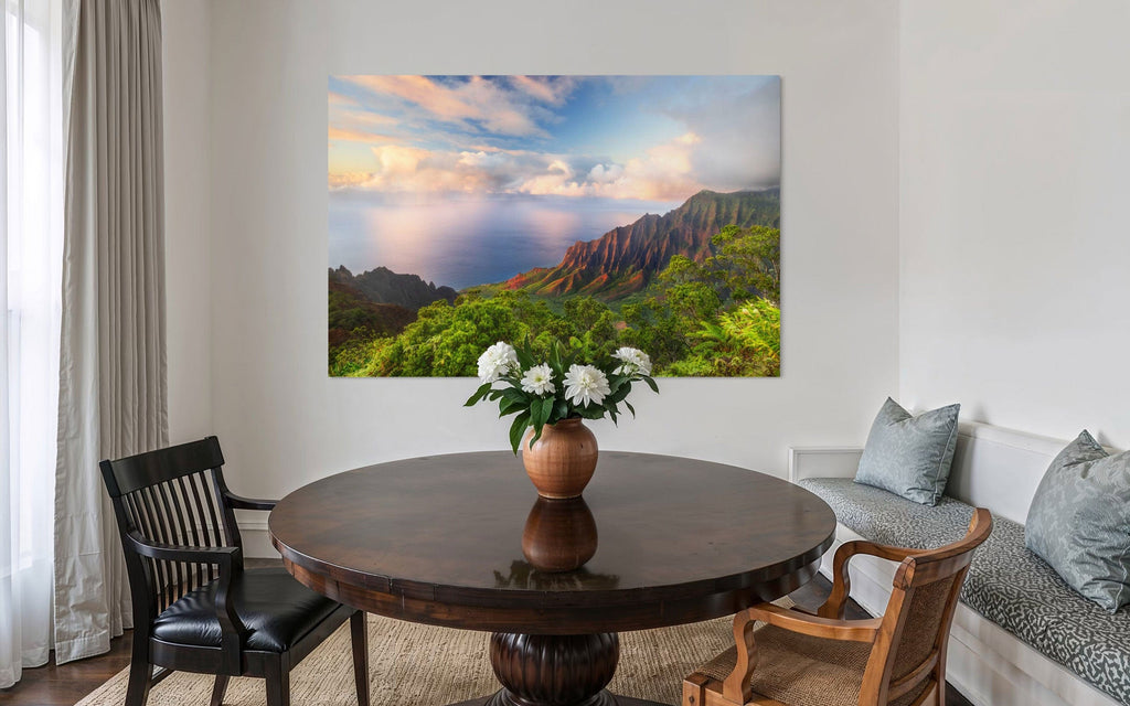 A piece of Kauai art showing a photo of sunset at the Napali Coast as seen from the Kalalau Valley Overlook hangs in a dining room.