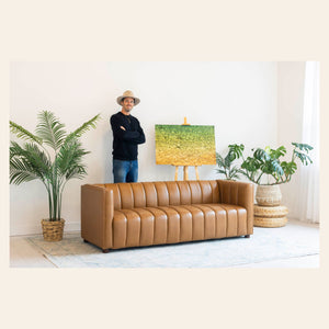 Lars Gesing with his piece of Kauai art showing the colors of the water on the ocean surface in a living room.