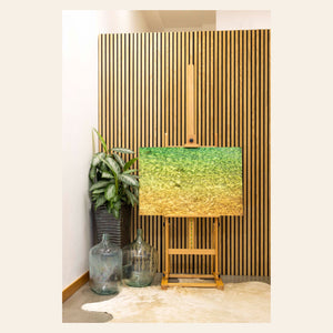 A piece of Kauai art by West Seattle art Lars Gesing showing the colors of the water on the ocean surface is shown in a coastal-inspired room.