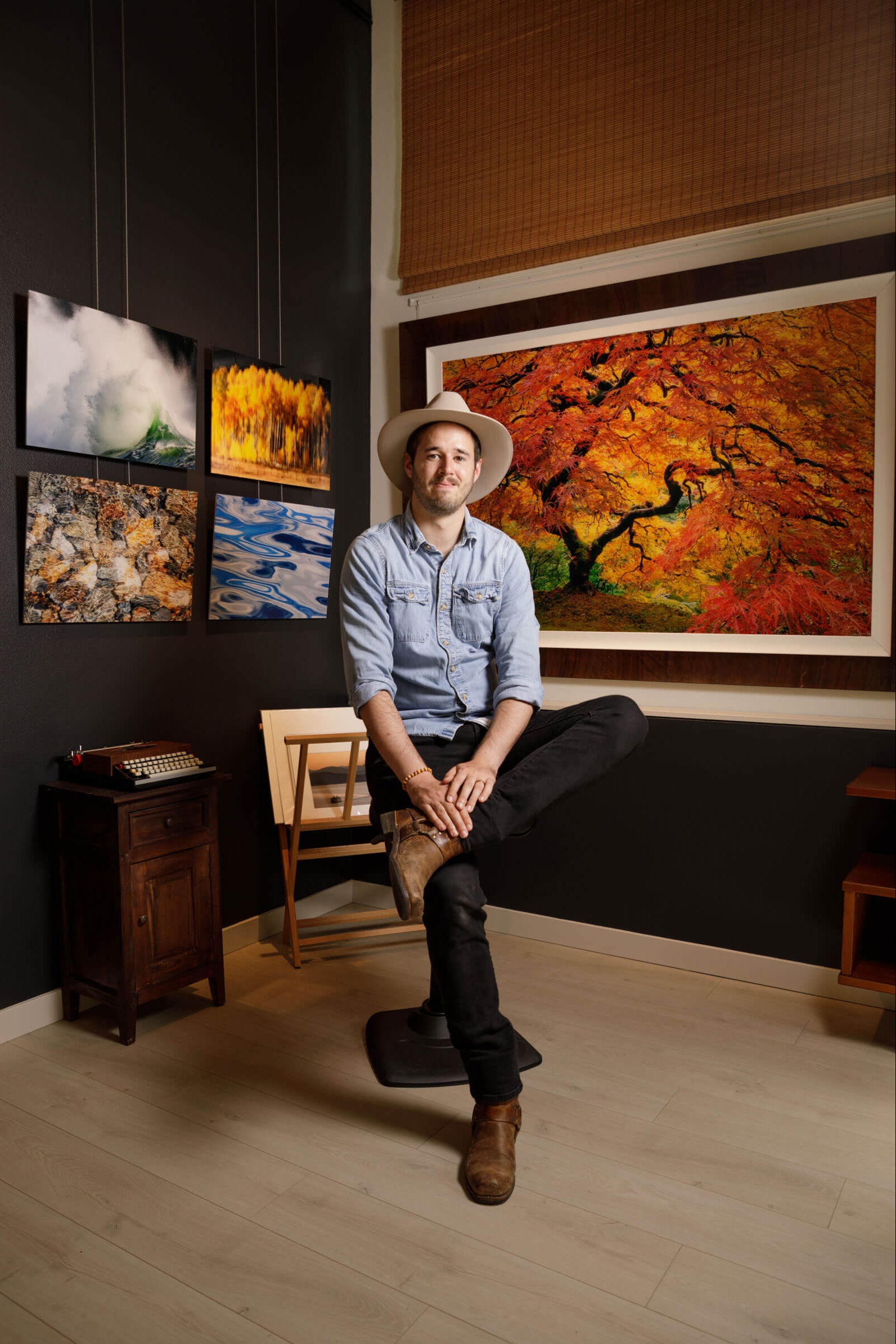 Artist Lars Gesing posing in his West Seattle gallery surrounded by colorful artworks.