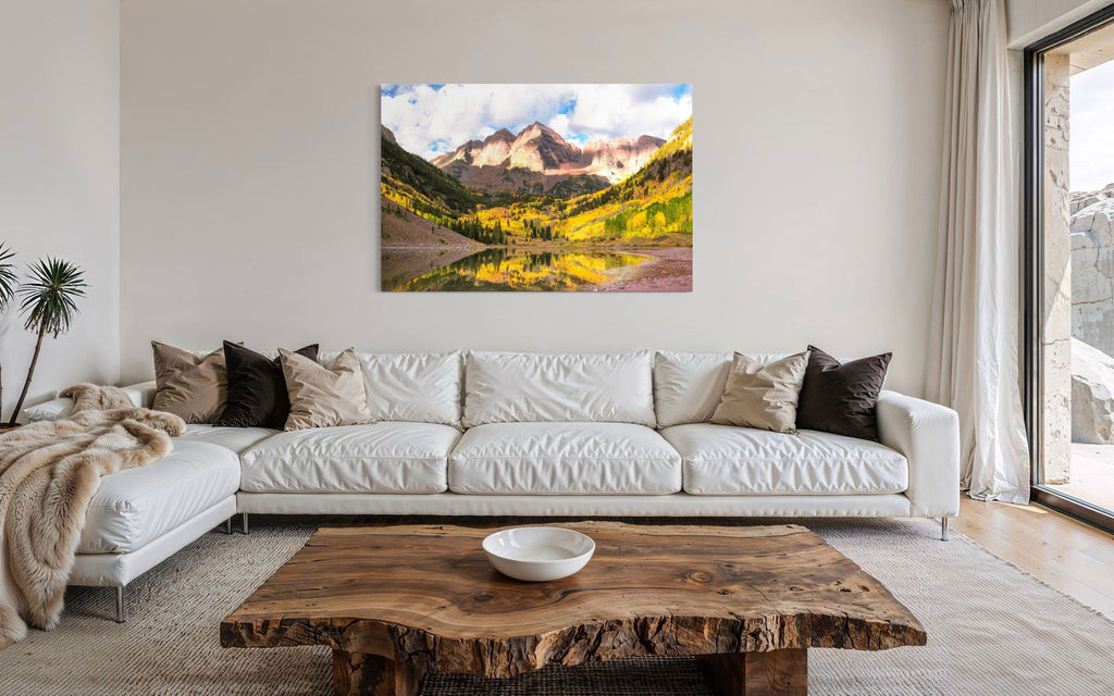 Stunning artwork of the Maroon Bells in Aspen during fall hangs in a living room over a couch.