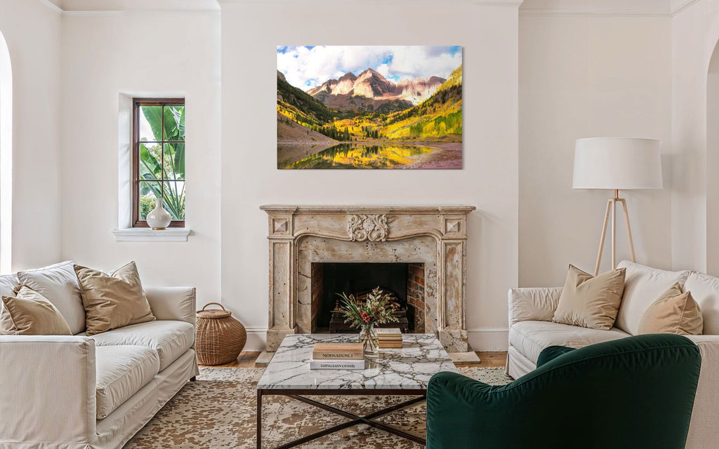 Stunning artwork of the Maroon Bells in Aspen during fall hangs over a fireplace.