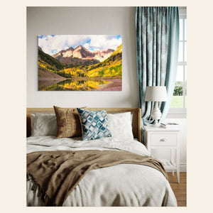 Stunning artwork of the Maroon Bells in Aspen during fall hangs in a bedroom.