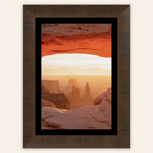 A piece of framed Moab art shows a Mesa Arch picture at sunrise.