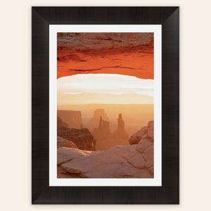 A piece of framed Moab art shows a Mesa Arch picture at sunrise.