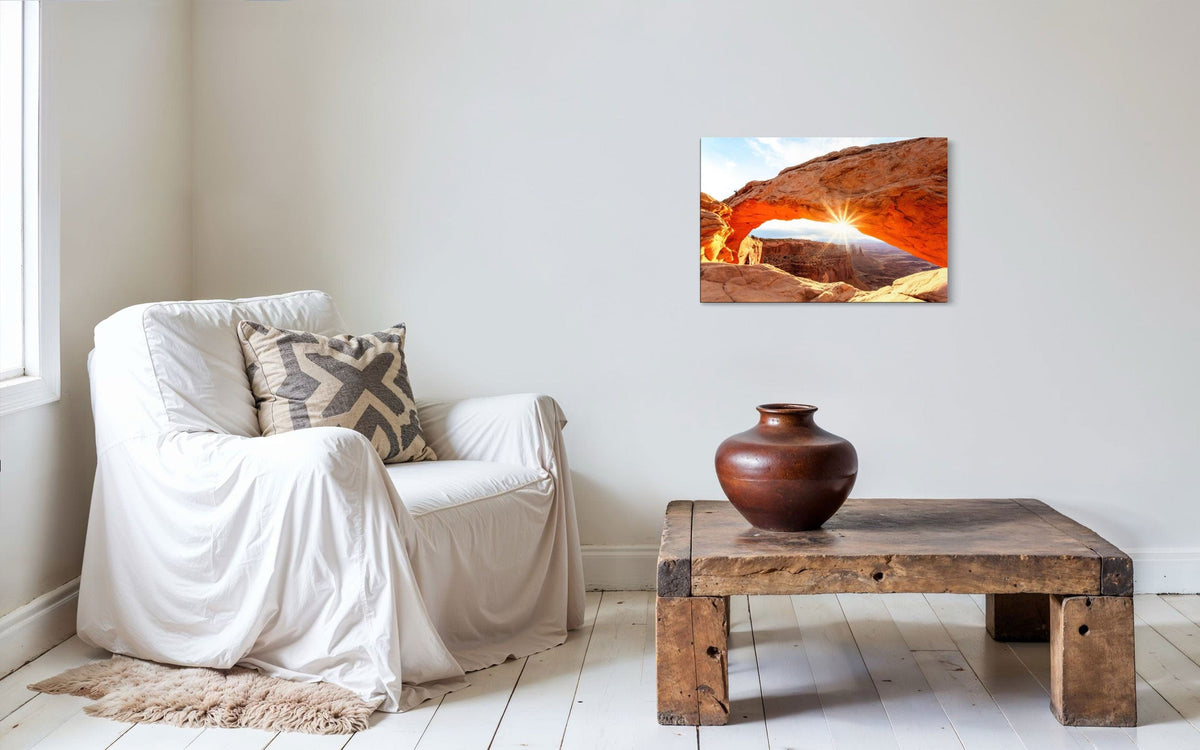 A piece of Moab art showing Mesa Arch in Canyonlands National Park hangs next to a comfy chair.
