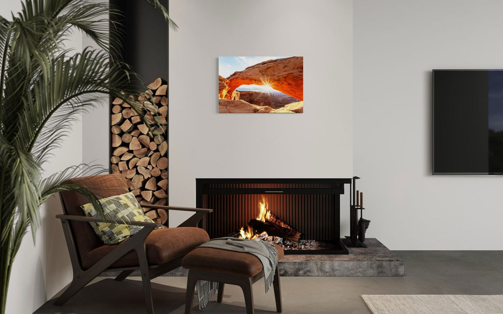 A piece of Moab art showing Mesa Arch in Canyonlands National Park hangs over a fireplace.