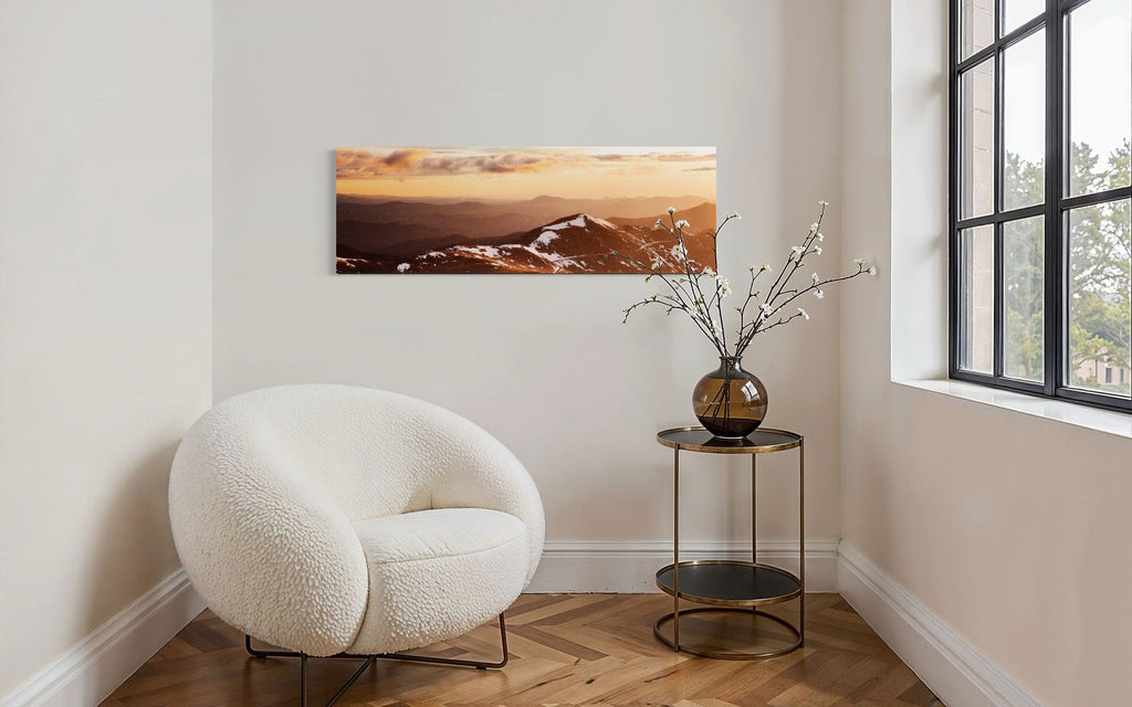 A piece of Colorado art showing a photo of Mount Evans at sunrise hangs above a comfy chair.