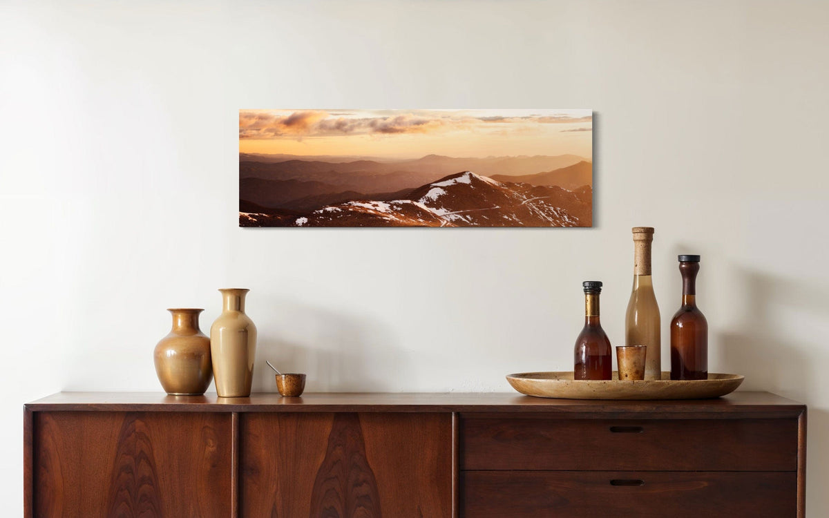 A piece of Colorado art showing a photo of Mount Evans at sunrise hangs in a dining room.
