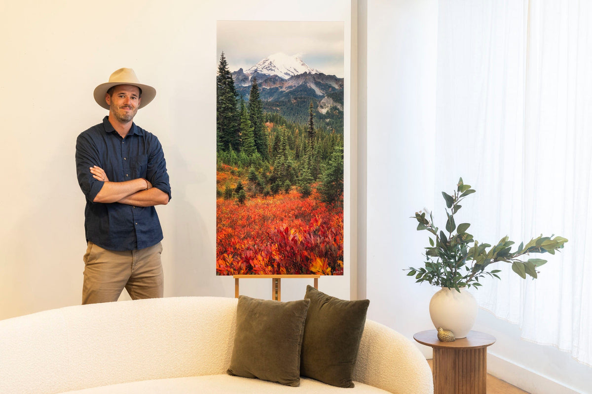 West Seattle artist Lars Gesing with a piece of large wall art showing a photo of the fall colors in Mount Rainier National Park.