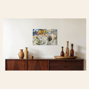 A piece of Rocky Mountain National Park art showing yellow aspen trees after snow in fall hangs in a dining room.