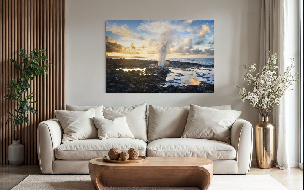 A piece of Kauai art showing a Spouting Horn photo hangs above a couch.