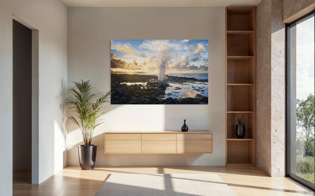 A piece of Kauai art showing a Spouting Horn photo hangs above a console.