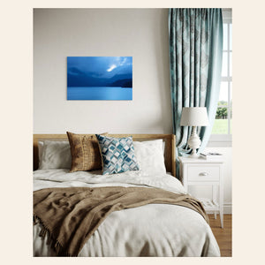 A piece of Vancouver Island art showing a lake photo hangs above a bed.
