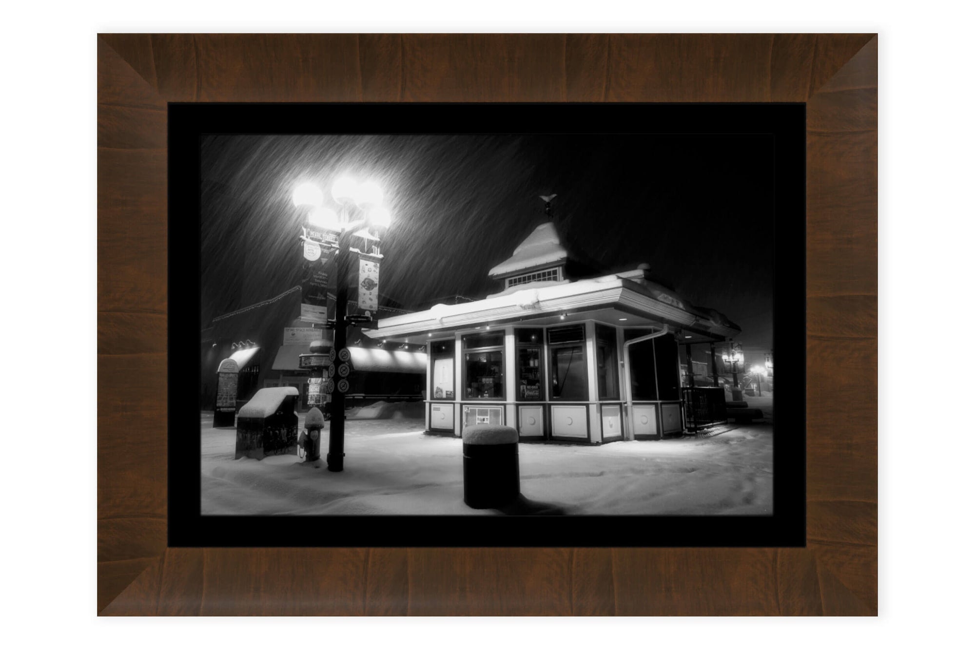 A piece of framed Boulder art shows a snowy Pearl Street Mall at night.
