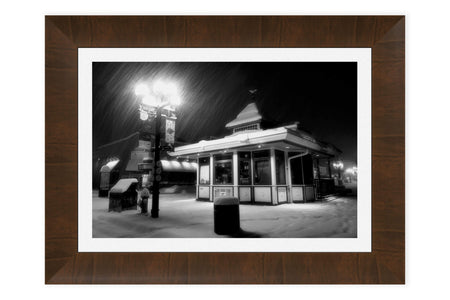 A piece of framed Boulder art shows a snowy Pearl Street Mall at night.