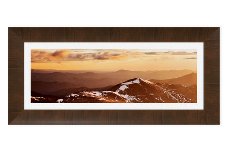 A piece of framed Colorado art shows a sunrise from Mount Evans looking toward Denver.