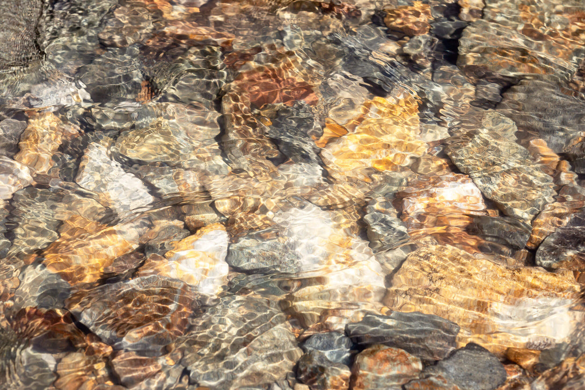 This piece of Telluride art shows glistening rocks in a Colorado River.